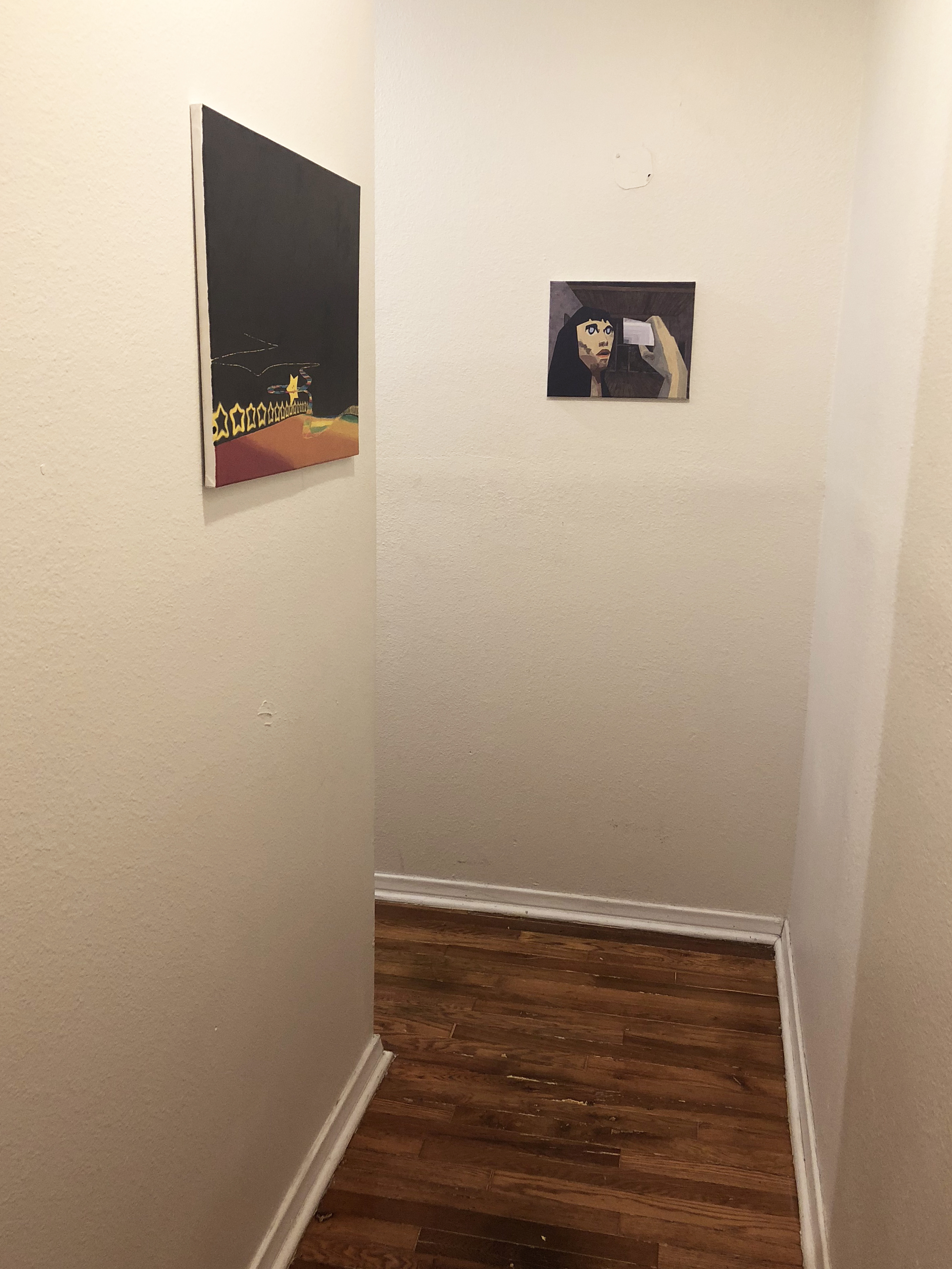 Two paintings hung in a narrow hallway on white walls